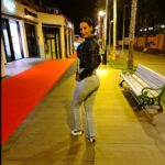 Diana Debreczeni walking through a lit promenade at night, wearing a black jacket and jeans