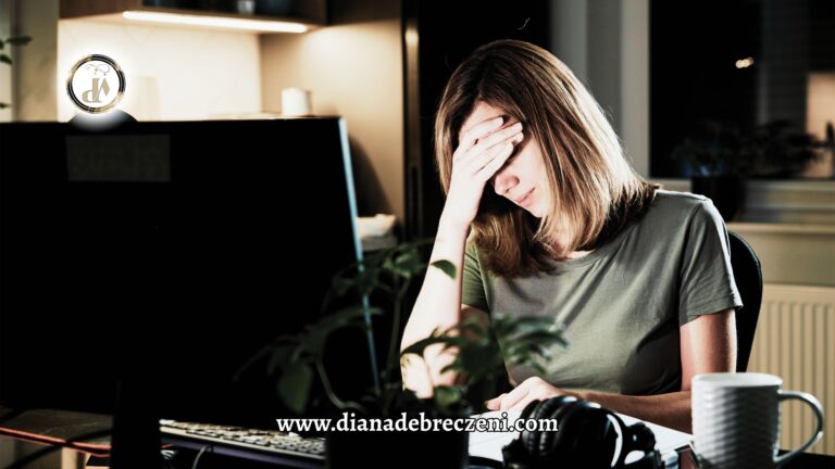A tired woman sitting at her desk with her head in her hand, symbolizing the stress and burnout caused by a toxic workplace culture.